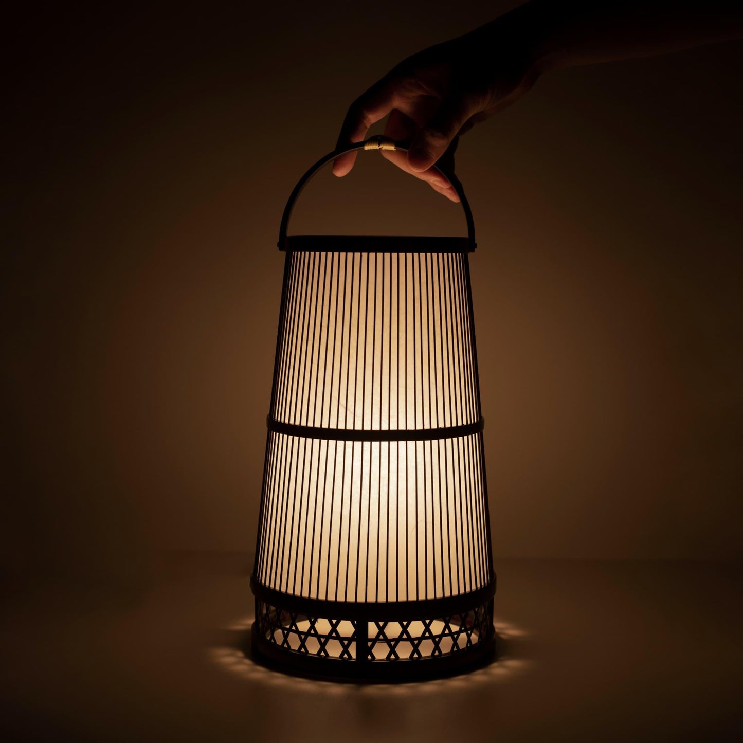 Hand holding a traditional Japanese bamboo lamp, handcrafted in Shizuoka with 800-year-old techniques.