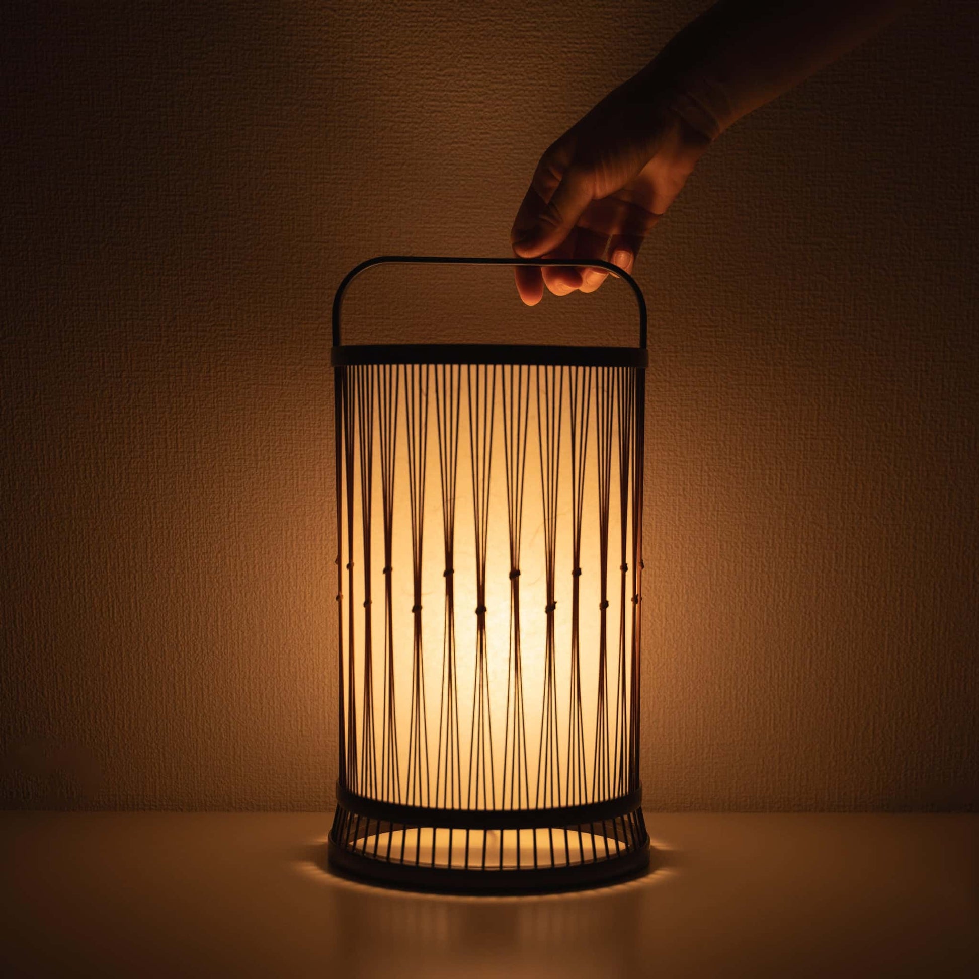 Hand holding a traditional Japanese bamboo lamp, handcrafted in Shizuoka with 800-year-old techniques.
