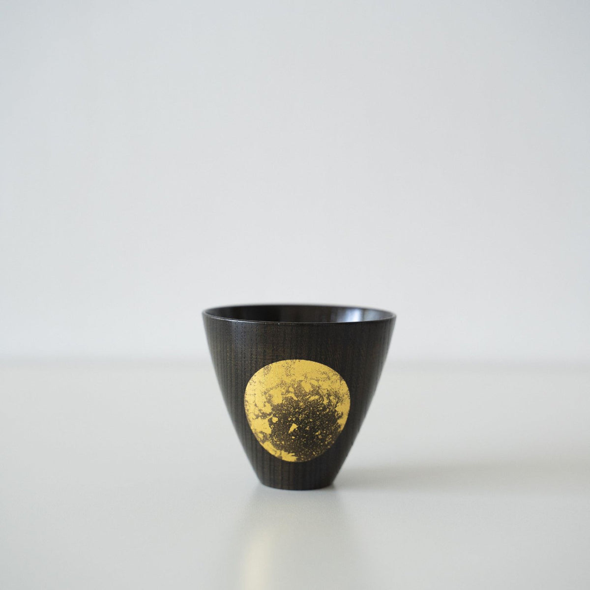 Japanse bladgoud sake kopje op een witte tafel