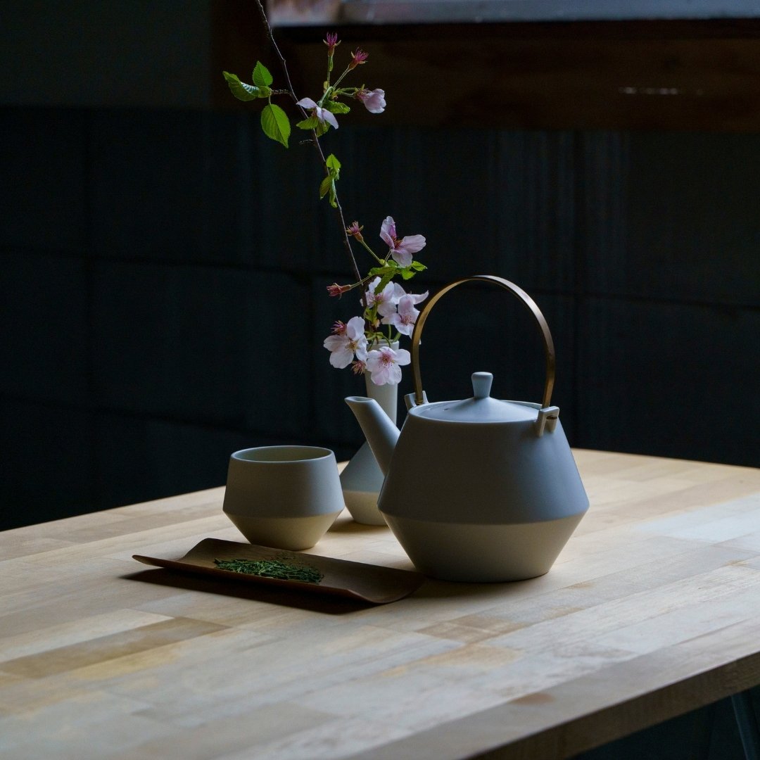 Japanese teapot set with yunomi tea cups and cherry blossoms on wooden table
