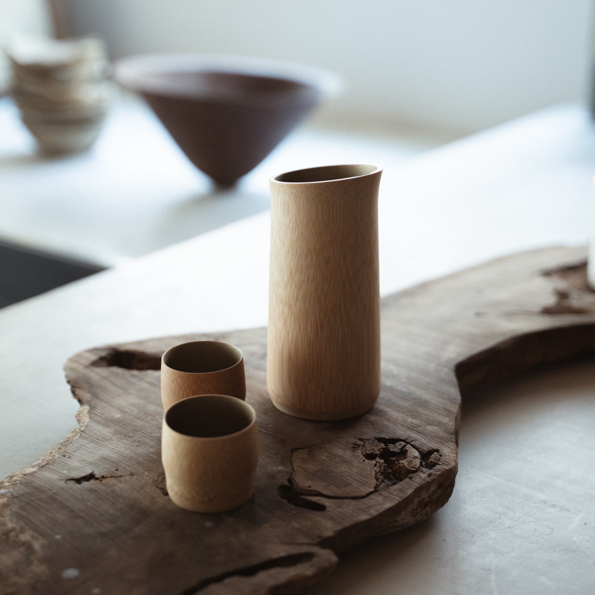 Japandi-style table setting with driftwood table, featuring a bamboo sake set crafted with traditional techniques from Kyoto, Japan.