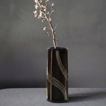Japanese bamboo vase titled "Flowing Water" displayed on a gray hotel table.