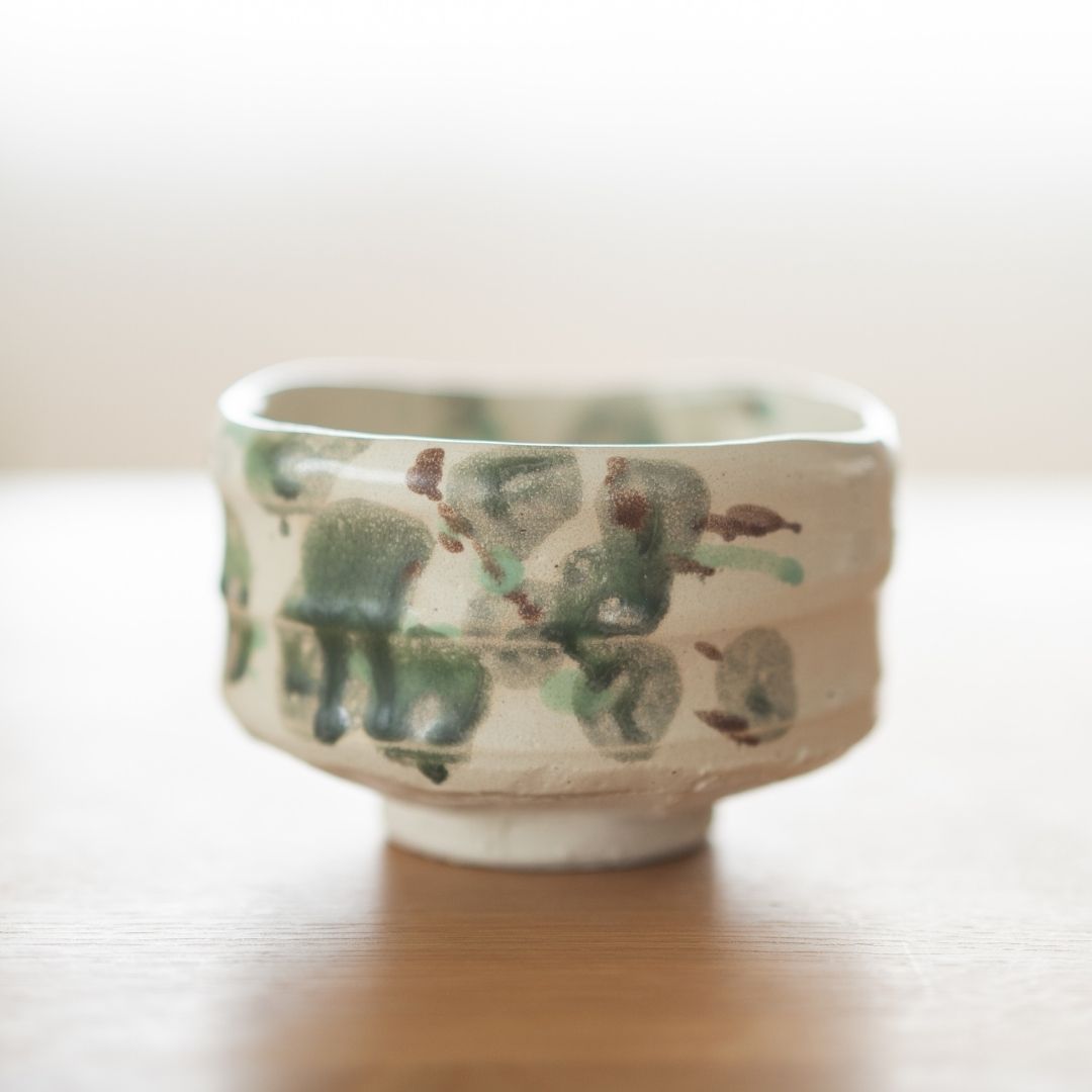 Side view of the "Forest" Japanese matcha bowl, featuring dark green and earth-brown glaze spots on rough Shino clay, evoking a mossy nature landscape.