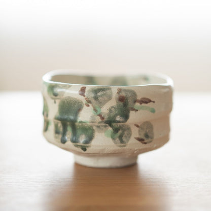 Side view of the "Forest" Japanese matcha bowl, featuring dark green and earth-brown glaze spots on rough Shino clay, evoking a mossy nature landscape.