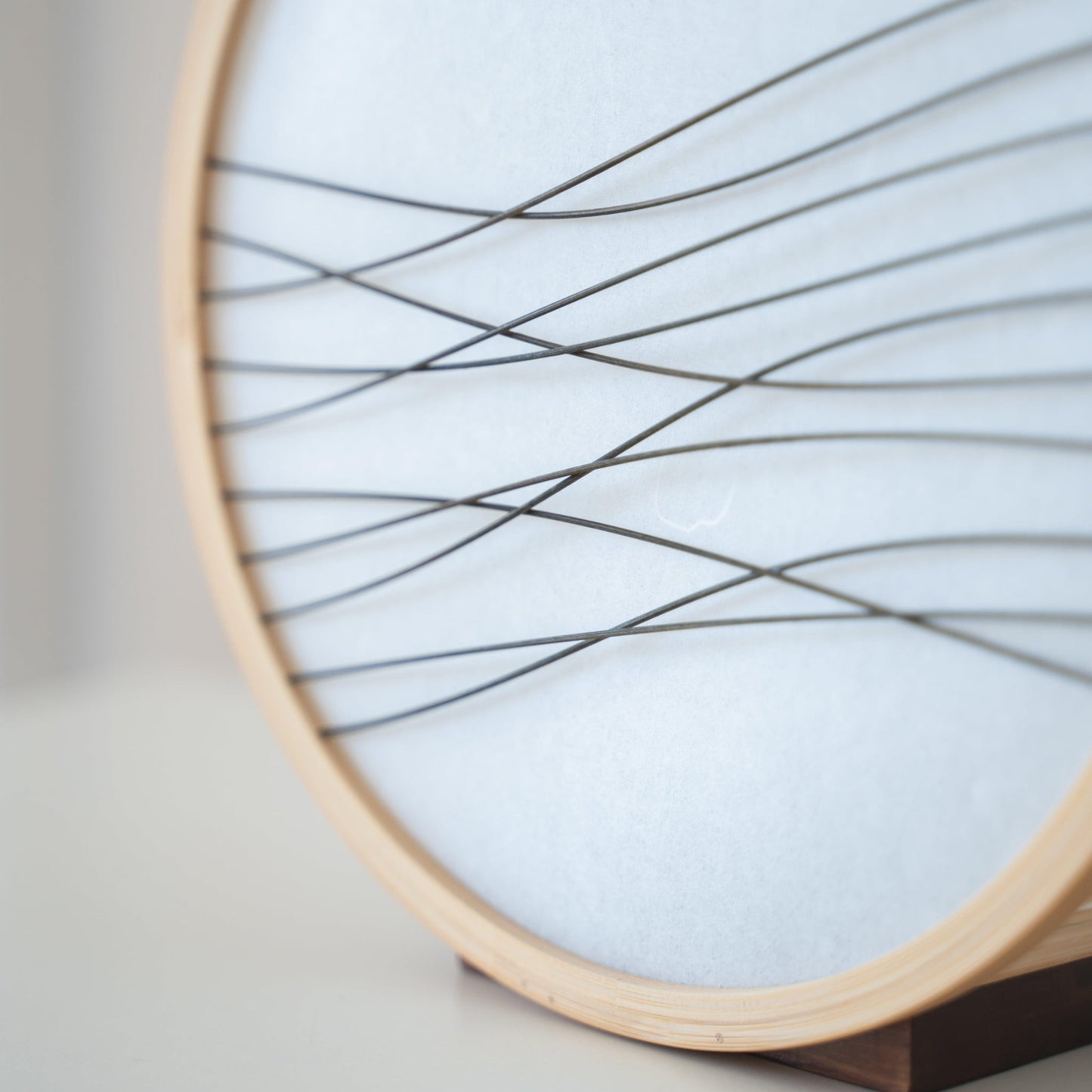 Traditional Japanese bamboo lamp handcrafted in Shizuoka with 800-year-old techniques. Circular wooden frame with washi paper shade featuring delicate bamboo accents. Simple yet elegant design casts a soft, warm glow.