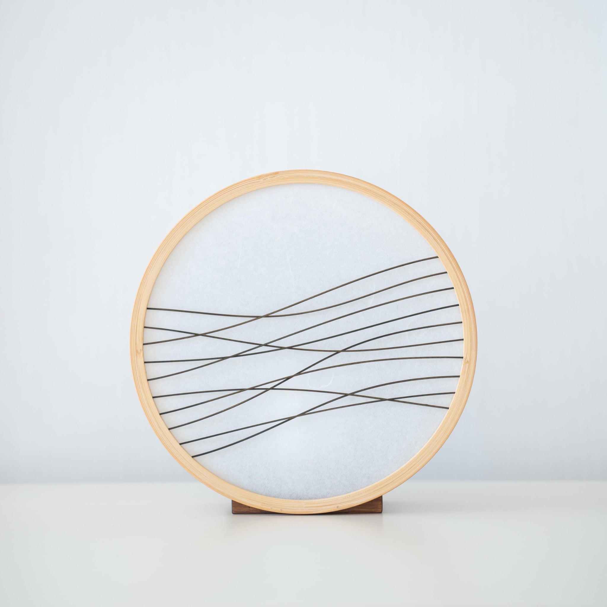 Traditional Japanese bamboo lamp handcrafted in Shizuoka with 800-year-old techniques. Circular wooden frame with washi paper shade featuring delicate bamboo accents. Simple yet elegant design casts a soft, warm glow.
