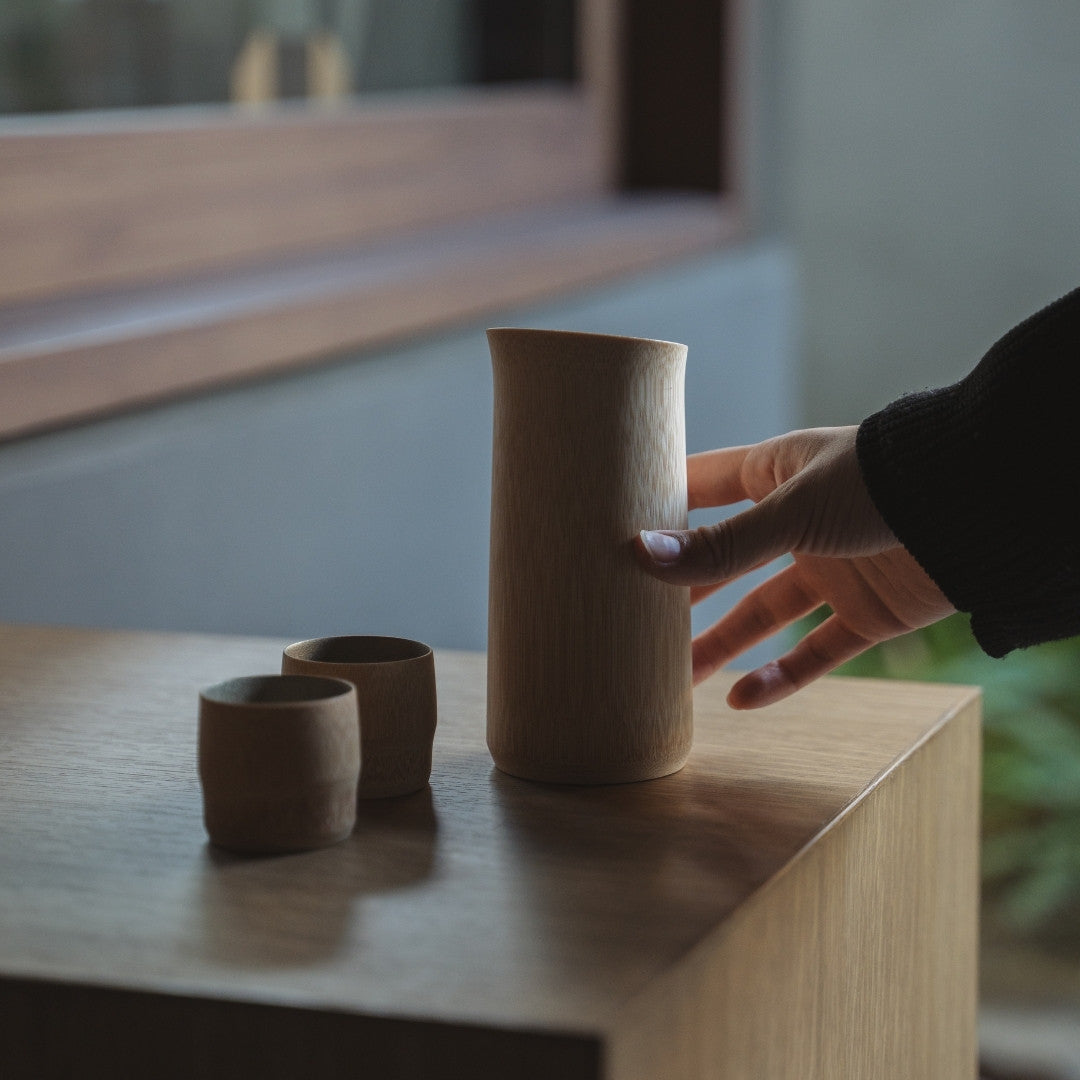 Japanese Bamboo Sake Set - tin Makie on a wooden table with a hand.