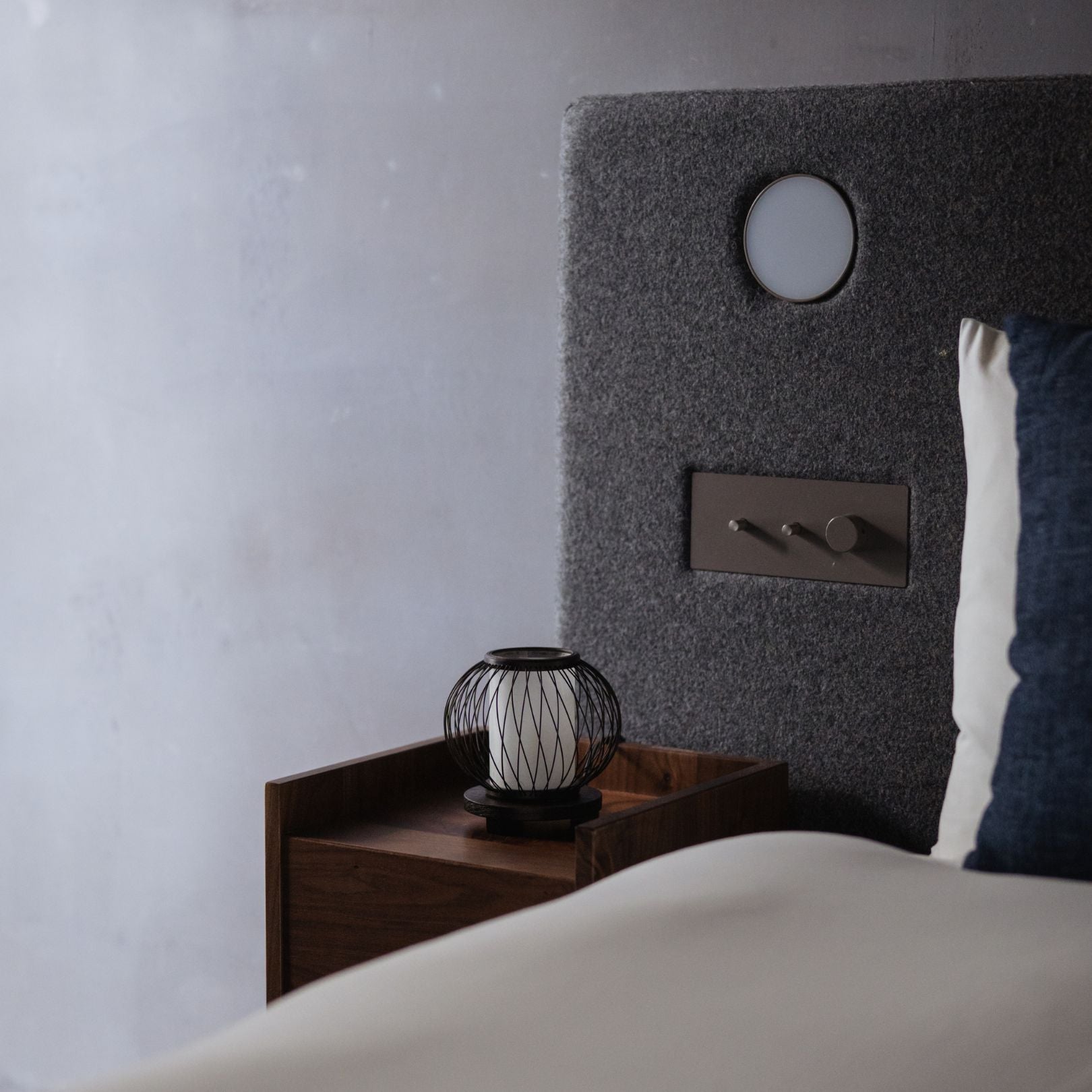 A Japanese bamboo table lamp placed on a bedside table in a Japandi-style bedroom.