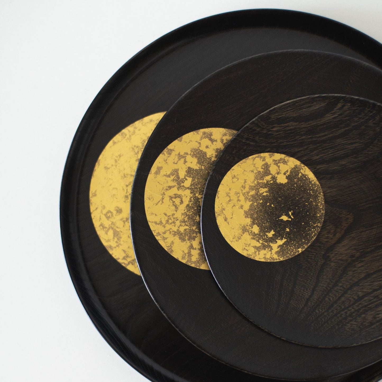 A close-up of a Japanese lacquerware plate featuring a moon design in gold leaf.