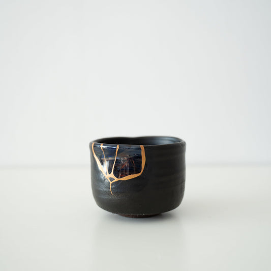 Black Kintsugi tea bowl repaired with blown glass using the Yobitsugi technique, the most challenging of Kintsugi techniques.