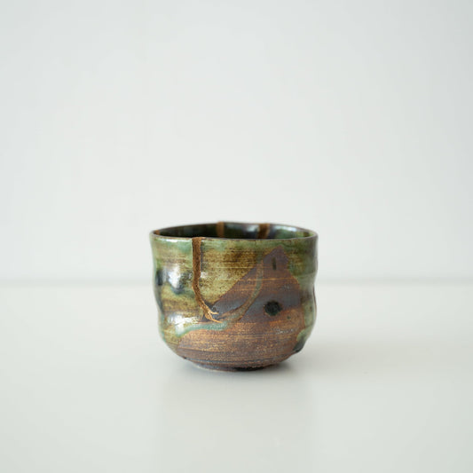 Deep green tea bowl repaired with Kintsugi, a traditional Japanese technique, showcasing the beauty of imperfection.
