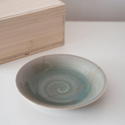 Gift set of a pale green bowl repaired with Kintsugi, a traditional Japanese technique, and a paulownia wood box.