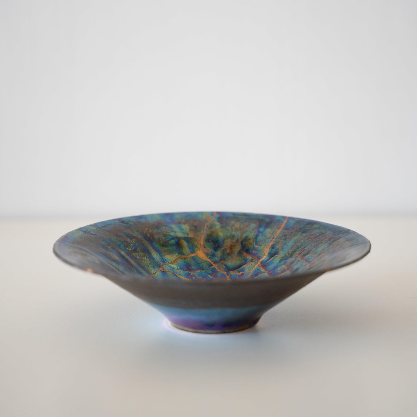 Iridescent bowl repaired with Kintsugi, a traditional Japanese technique that embraces the beauty of imperfection.