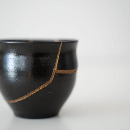 Japanese sake cup repaired with Kintsugi, a traditional Japanese technique, featuring black lacquer 