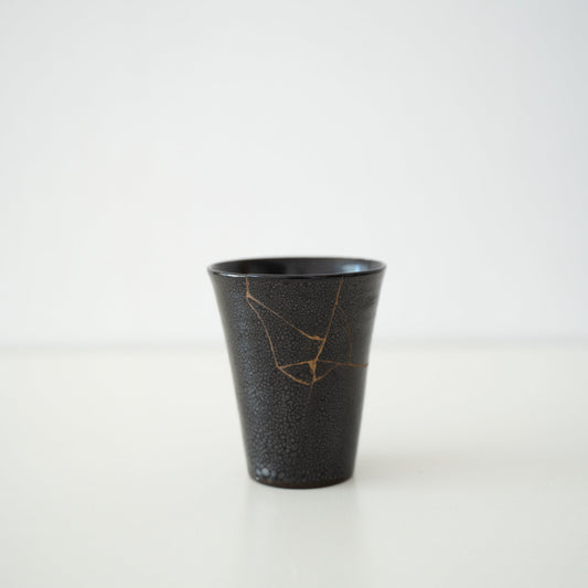 Japanese cup repaired with Kintsugi, a traditional Japanese technique, featuring black lacquer and named "Shikkoku Rai" (Jet-Black Thunder).