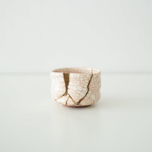 White tea bowl repaired with Kintsugi, a traditional Japanese technique, showcasing the golden joinery.