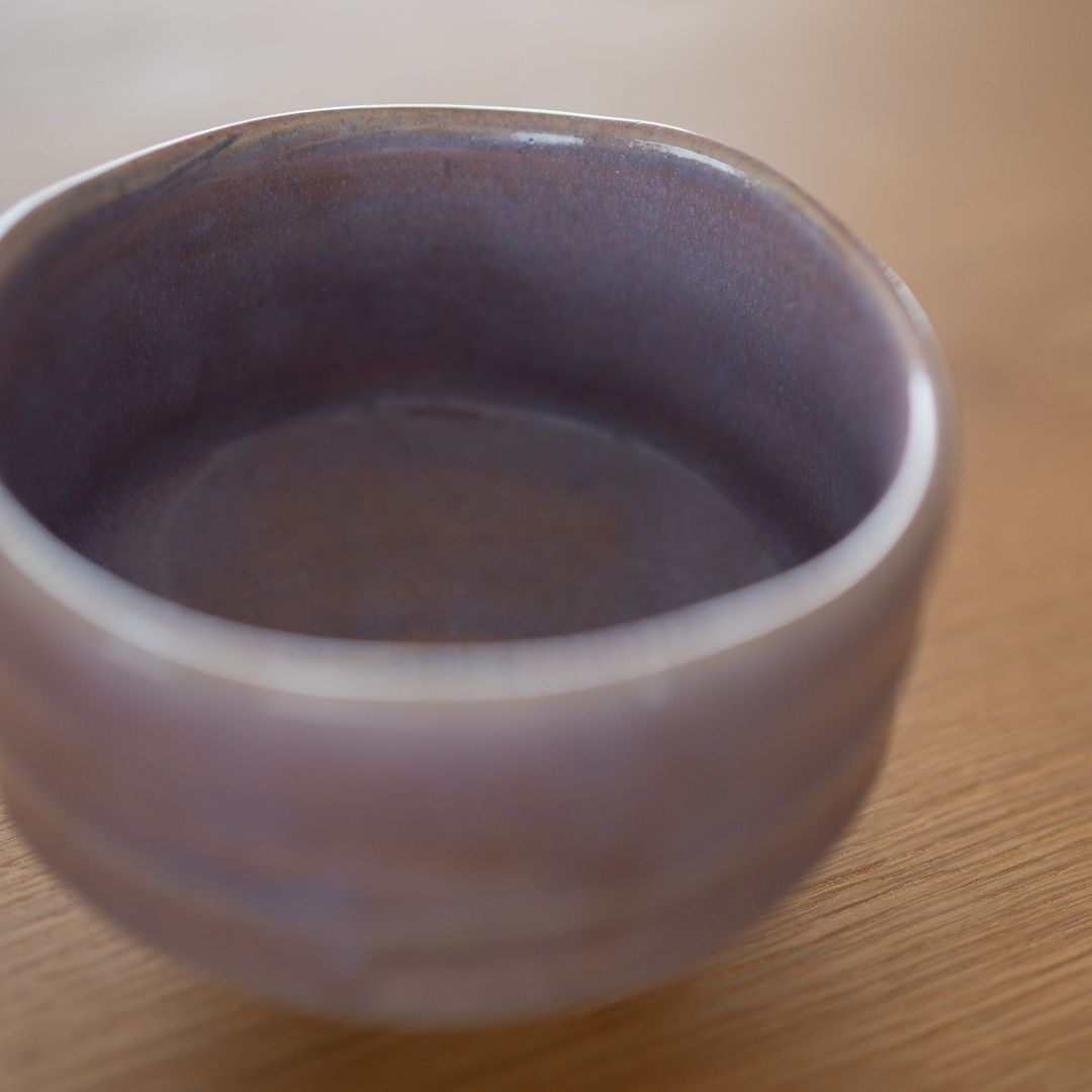 Close-up of a Pale Violet Japanese matcha bowl by Shinzan Kiln, showing the Mino Ware's glossy light purple glaze and warm earthen tones on the textured surface.