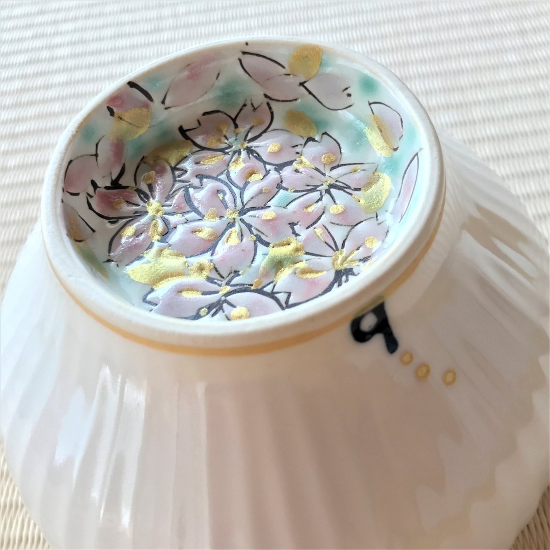 A Japanese matcha bowl “Waraku” Flower by Buzan Kiln, decorated with hand-painted sakura blossoms and gold accents, crafted in Mino Ware porcelain for spring.