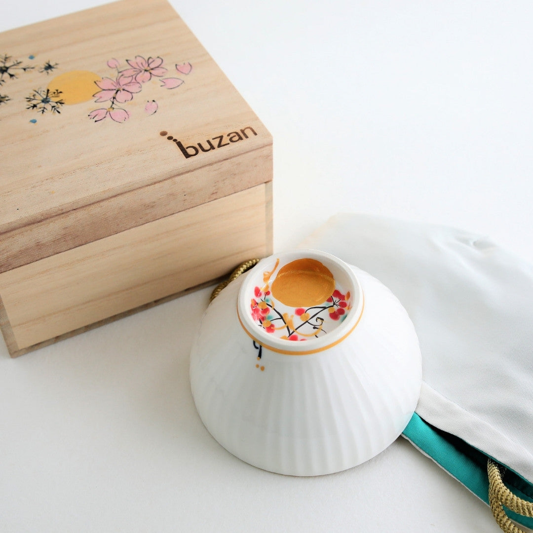 A Japanese matcha bowl “Waraku” Moon handcrafted by Buzan Kiln, paired with a hand-painted wooden box and silk pouch, perfect as a luxury tea ceremony gift.