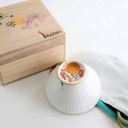 A Japanese matcha bowl “Waraku” Moon handcrafted by Buzan Kiln, paired with a hand-painted wooden box and silk pouch, perfect as a luxury tea ceremony gift.