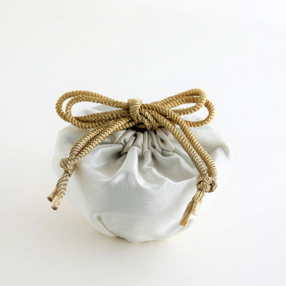 A Japanese matcha bowl “Waraku” wrapped in an elegant silk pouch with a golden cord, representing the refined beauty and tradition of Mino Ware ceramics.