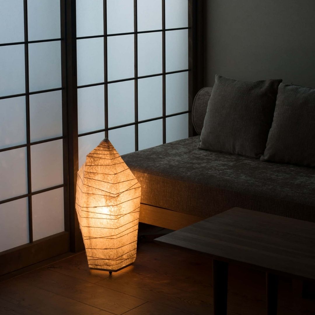 Japansk gulvlampe "PAPAER STONE", der udsender et varmt skær i en svagt oplyst stue i japansk stil