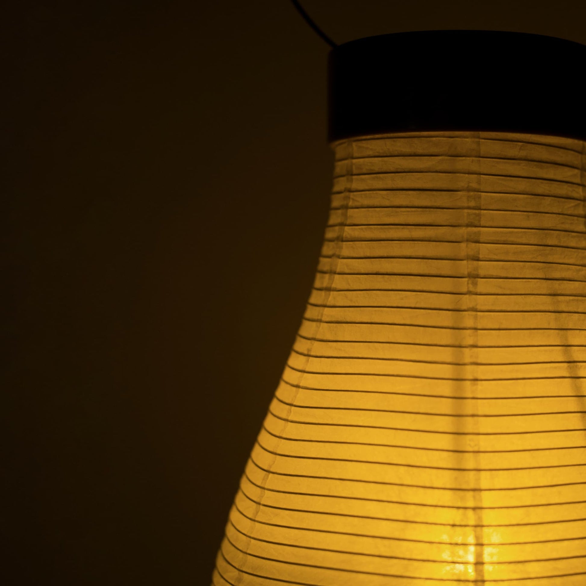 A traditional Japanese paper lantern casting warm light in a dark room