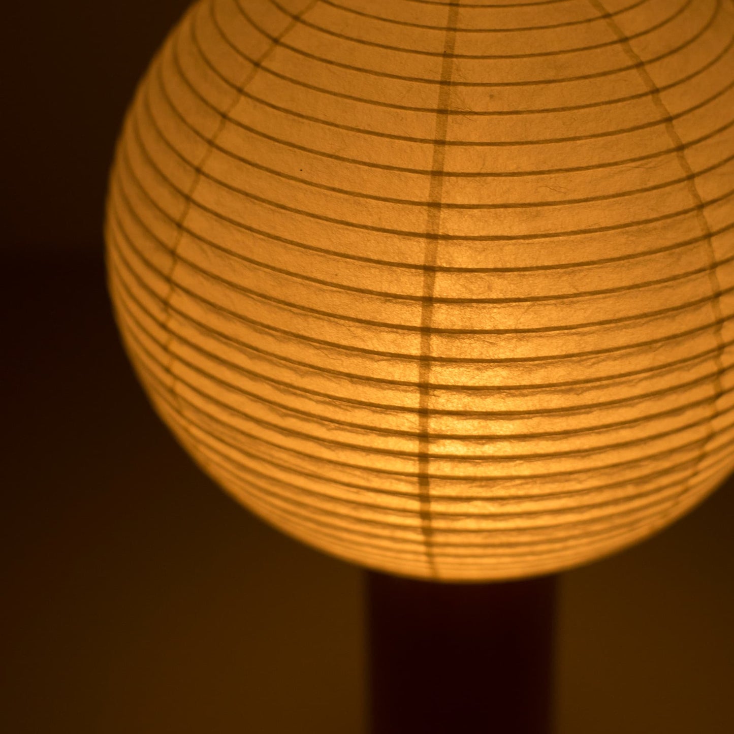 Close-up of the "TORCHIN CIRCLE"  paper lamp, highlighting the unique texture of the washi paper shade and the warm light it emits.