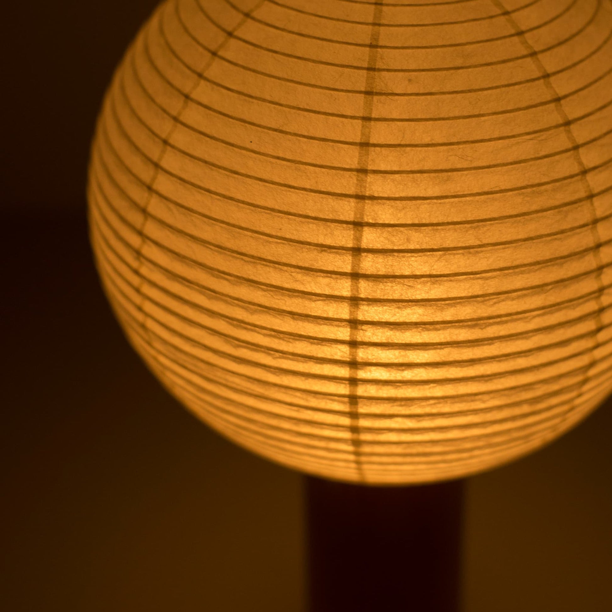 Close-up of the "TORCHIN CIRCLE"  paper lamp, highlighting the unique texture of the washi paper shade and the warm light it emits.