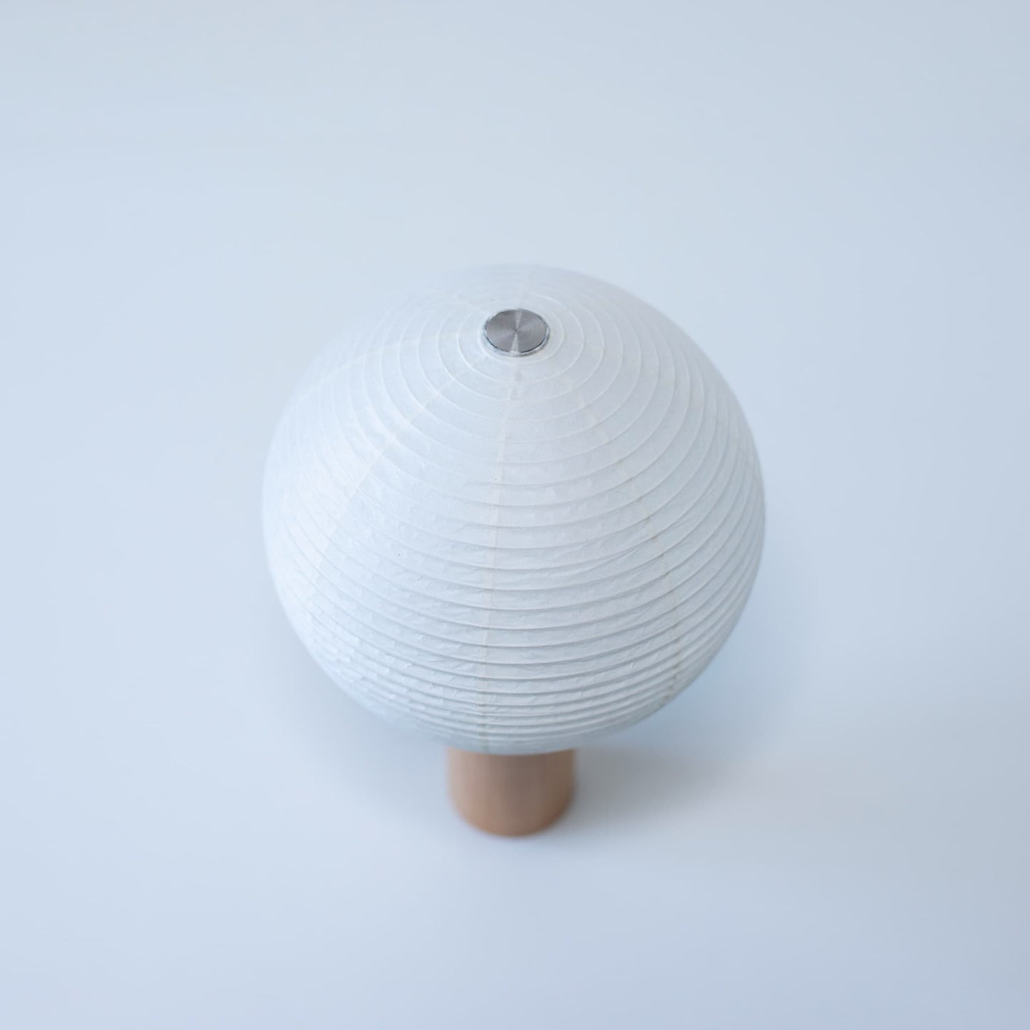 Paper table lamp "TORCHIN CIRCLE" with a unique spherical white washi paper shade and a wooden handle, handcrafted using traditional Yame lantern techniques in Fukuoka, Japan.