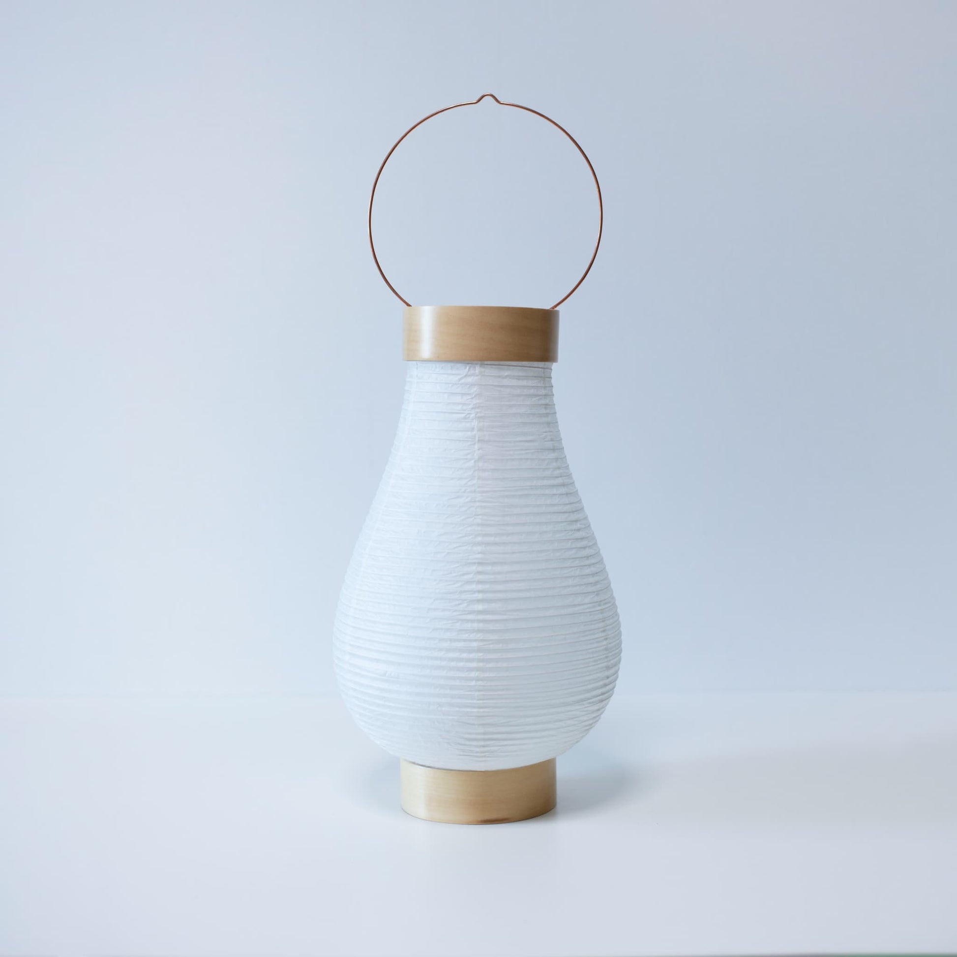 A traditional Japanese paper lantern against a bright white wallpaper