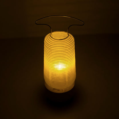 A traditional Japanese paper lantern emitting warm light in a dim room