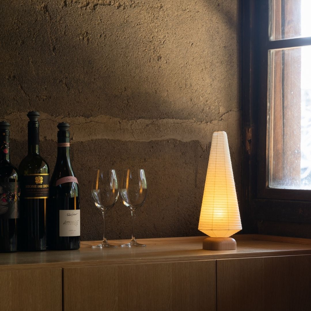 Japanese Paper Table Lamp "Tree" with wine bottles and wine glasses on a wooden shelf in the corner of a room.