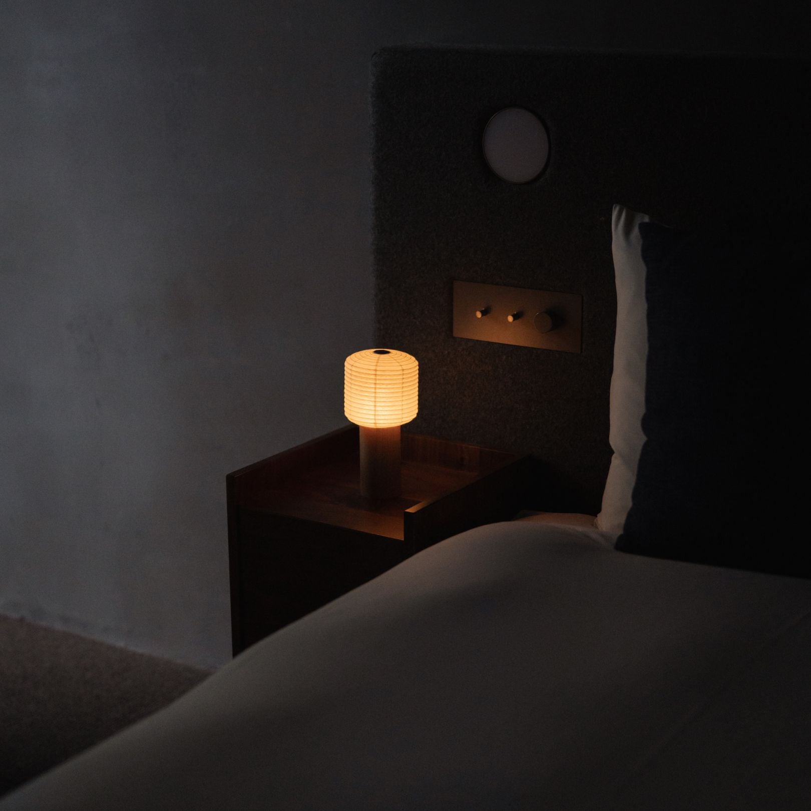 A Japanese paper touch lamp "TORCHIN SQUARE" on a bedside table. 