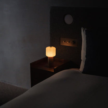 A Japanese paper touch lamp "TORCHIN SQUARE" on a bedside table. 