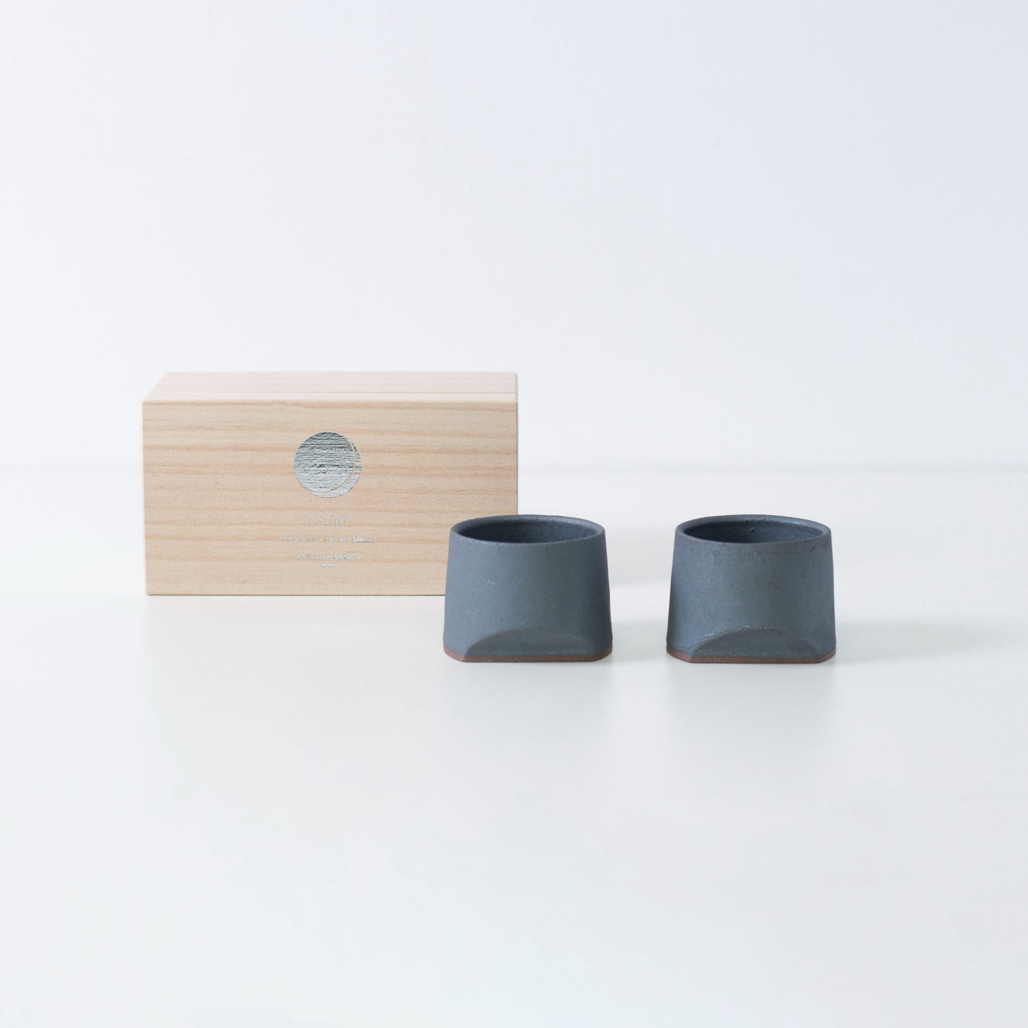 Gift set of two iron-colored sake cups, crafted using traditional Japanese roof tile techniques, presented in a paulownia wood box.