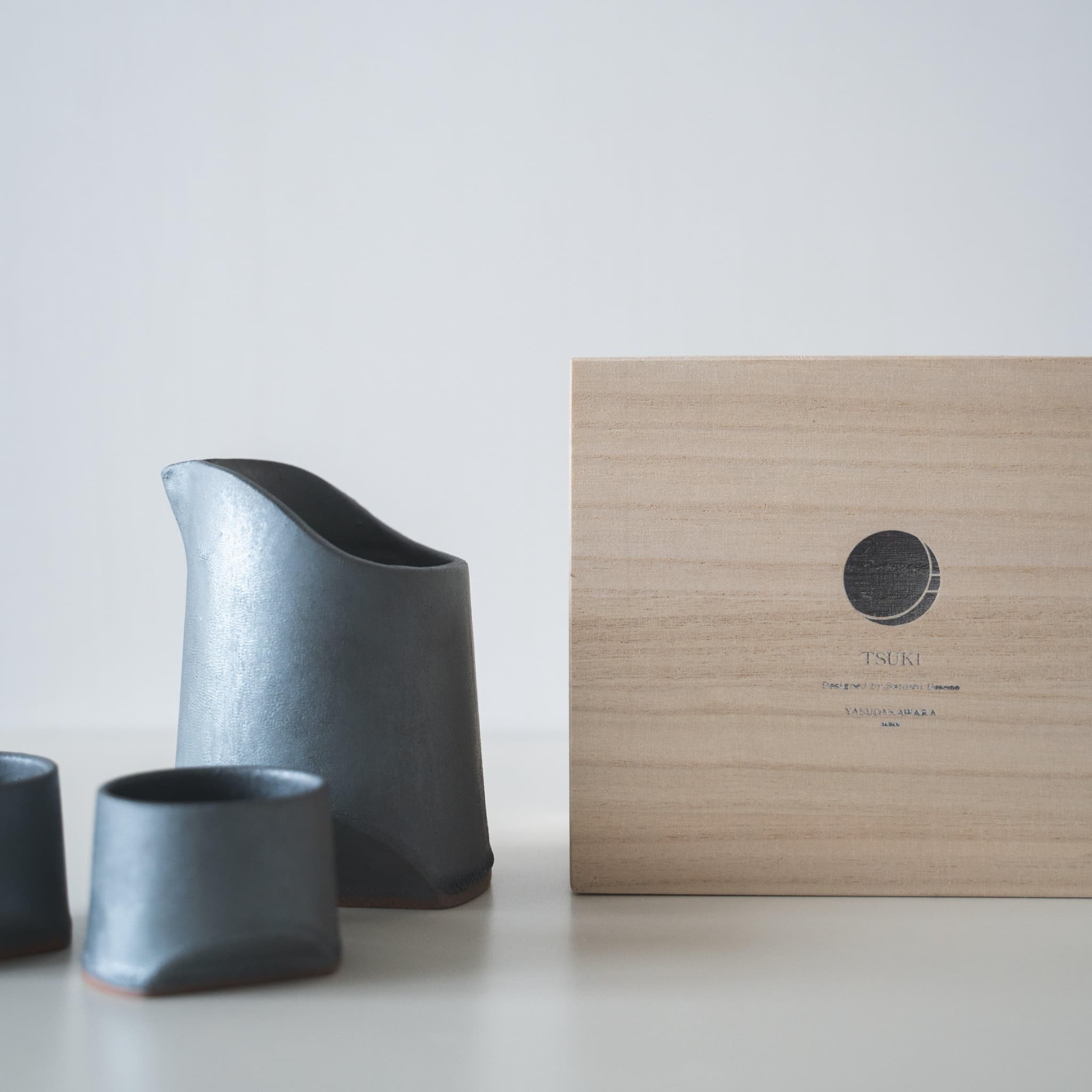 Gift set of iron-colored sake pitcher and two cups, crafted using traditional Japanese roof tile techniques, presented in a paulownia wood box.