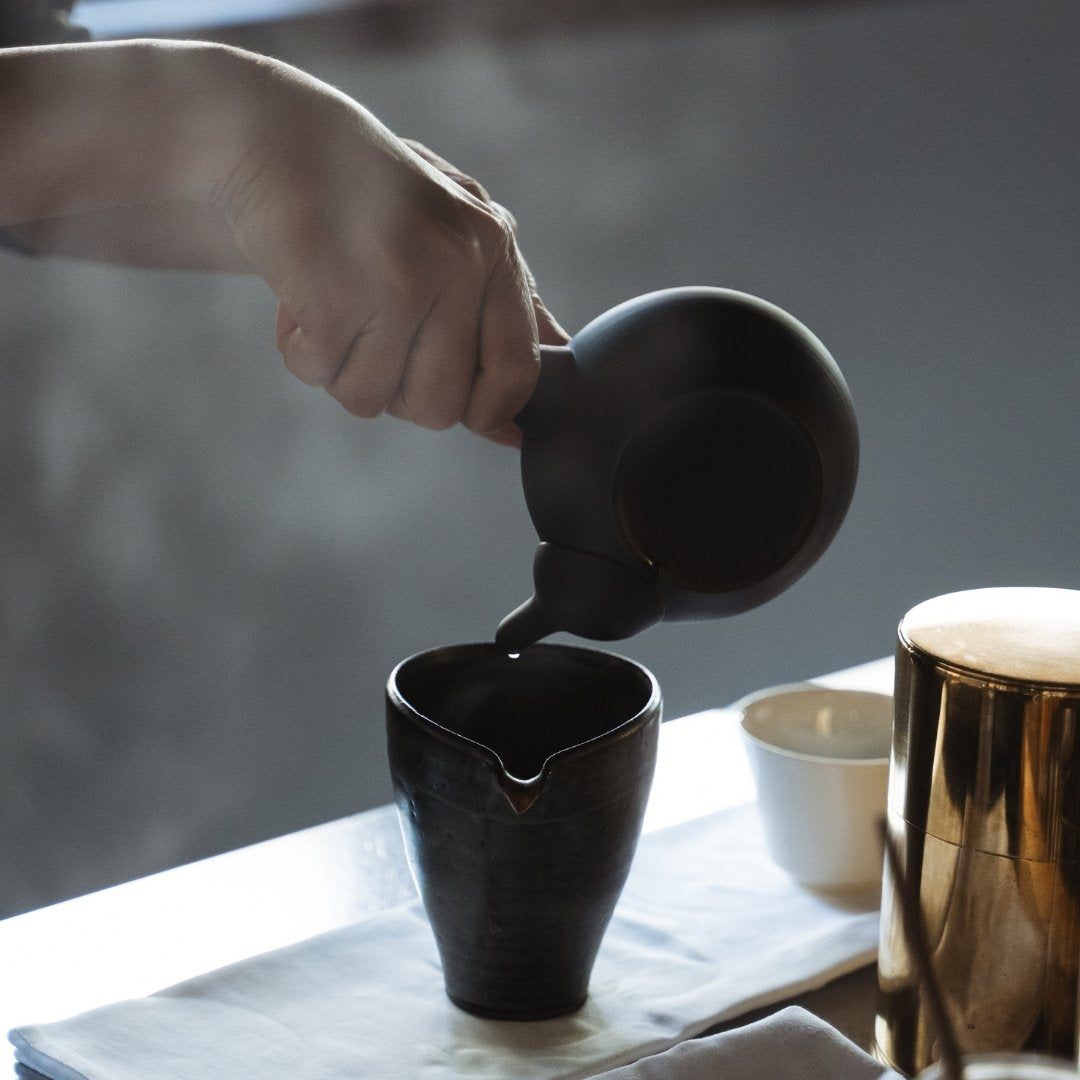 Pouring Japanese tea by Handcrafted Japanese teapot Black with Hands