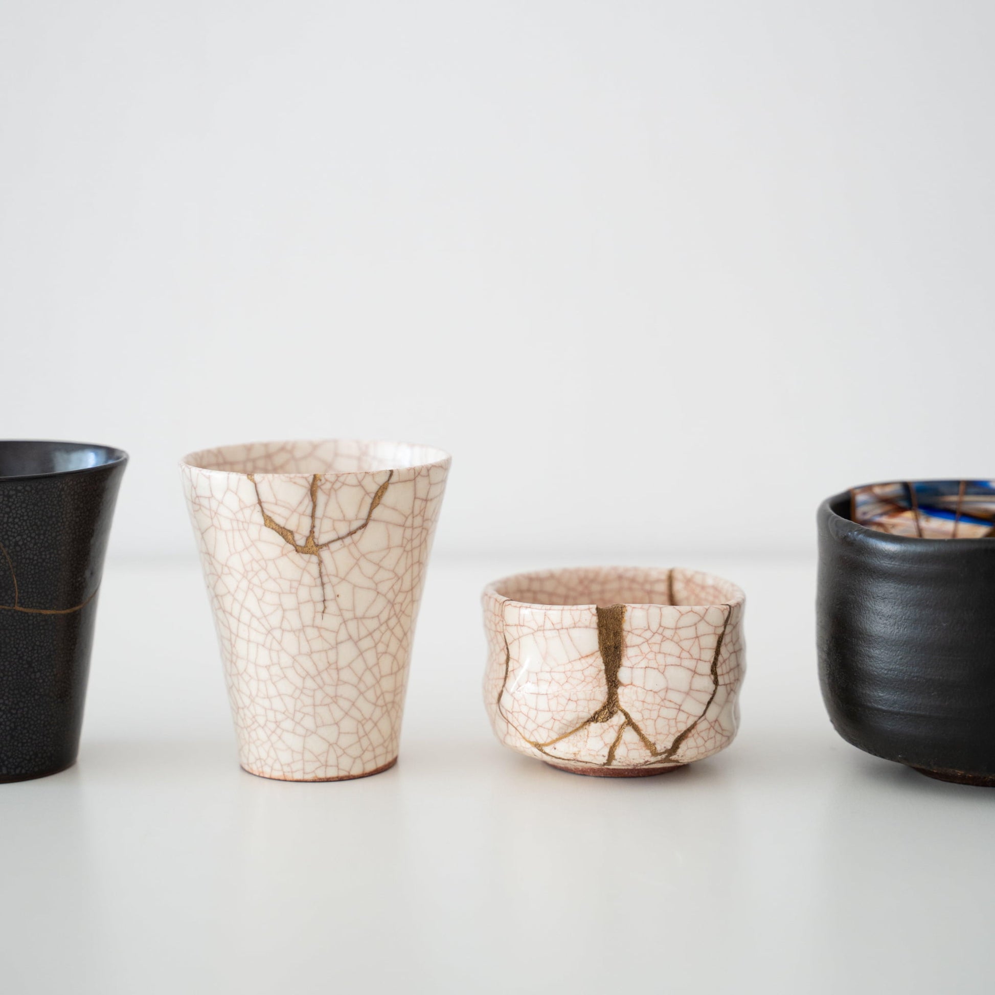 White and black kintsugi cups and teabowls on a white table