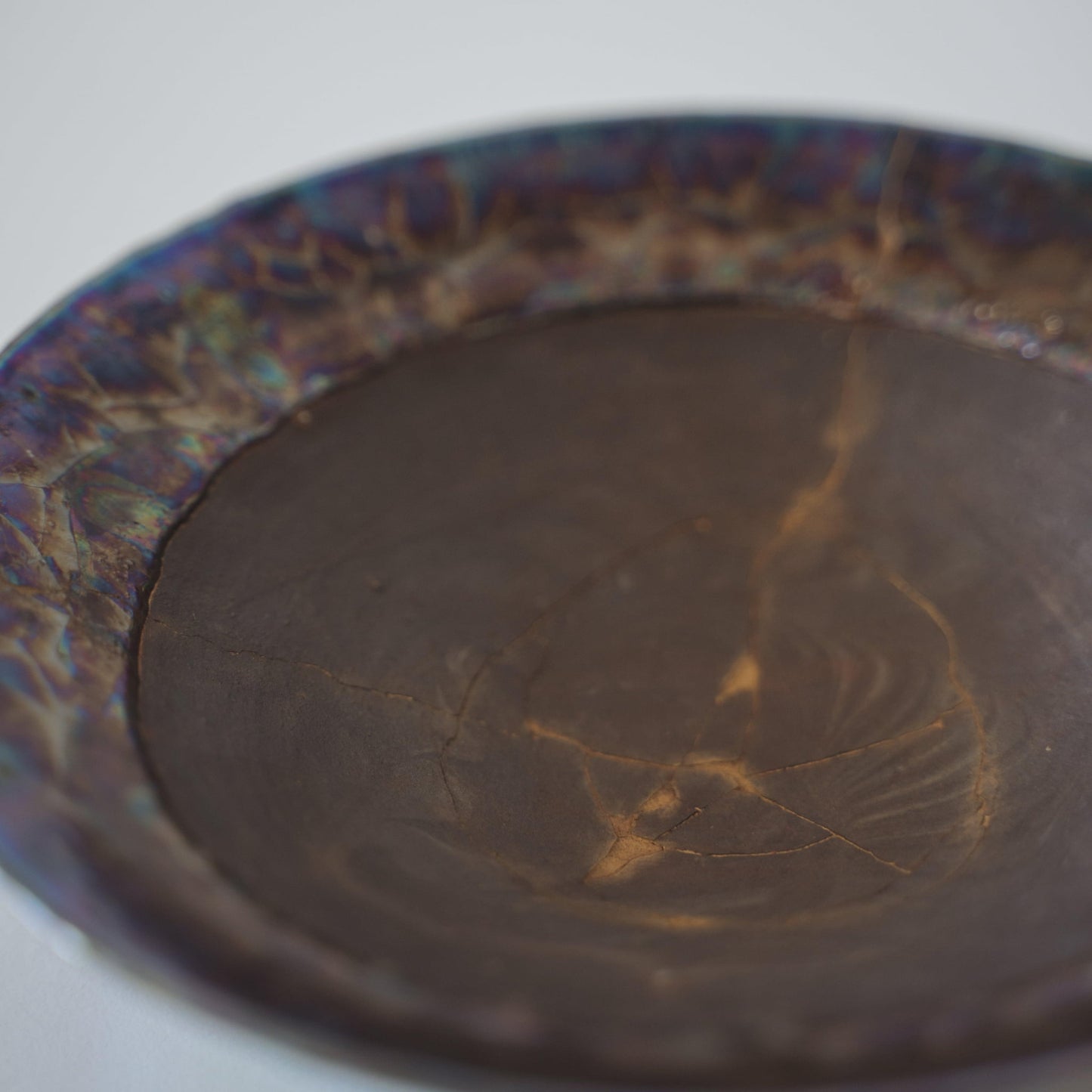 Japanese Kintsugi bowl in deep brown with a gold repair, showcasing the beauty of imperfection.