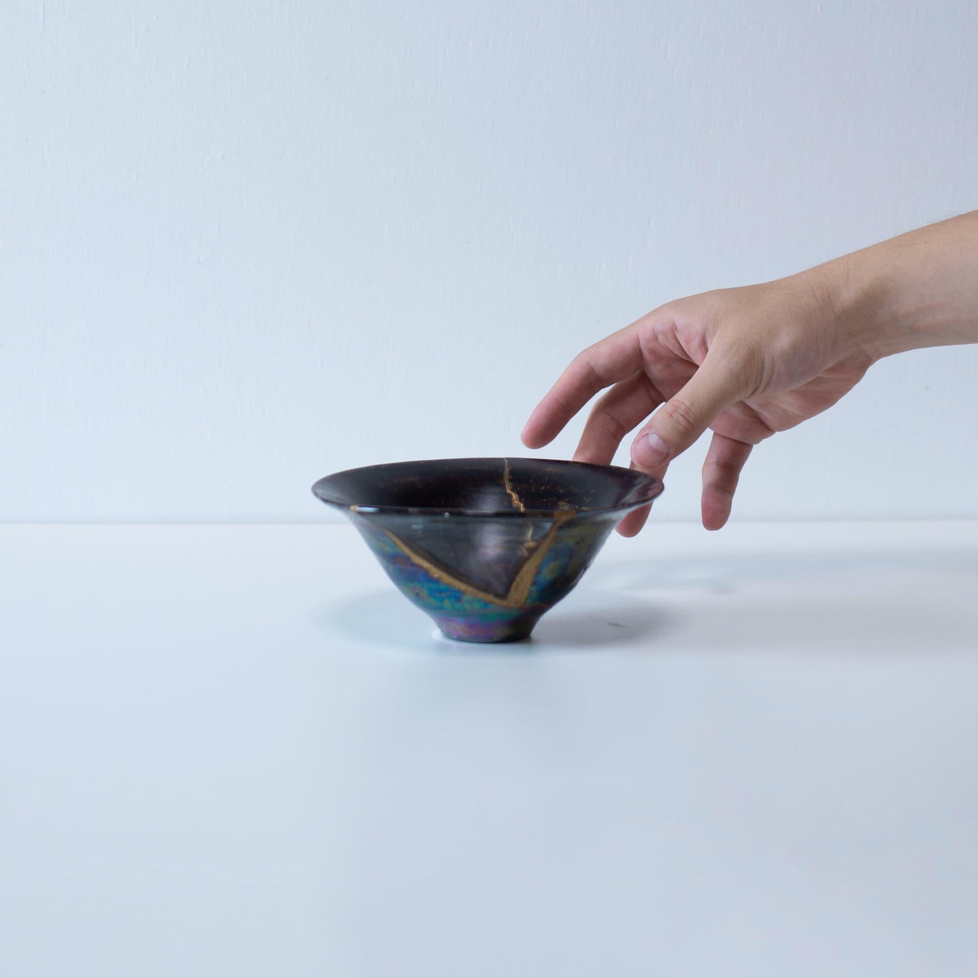 A hand gently cradling a Kintsugi bowl, showcasing the delicate nature of this unique repair technique.