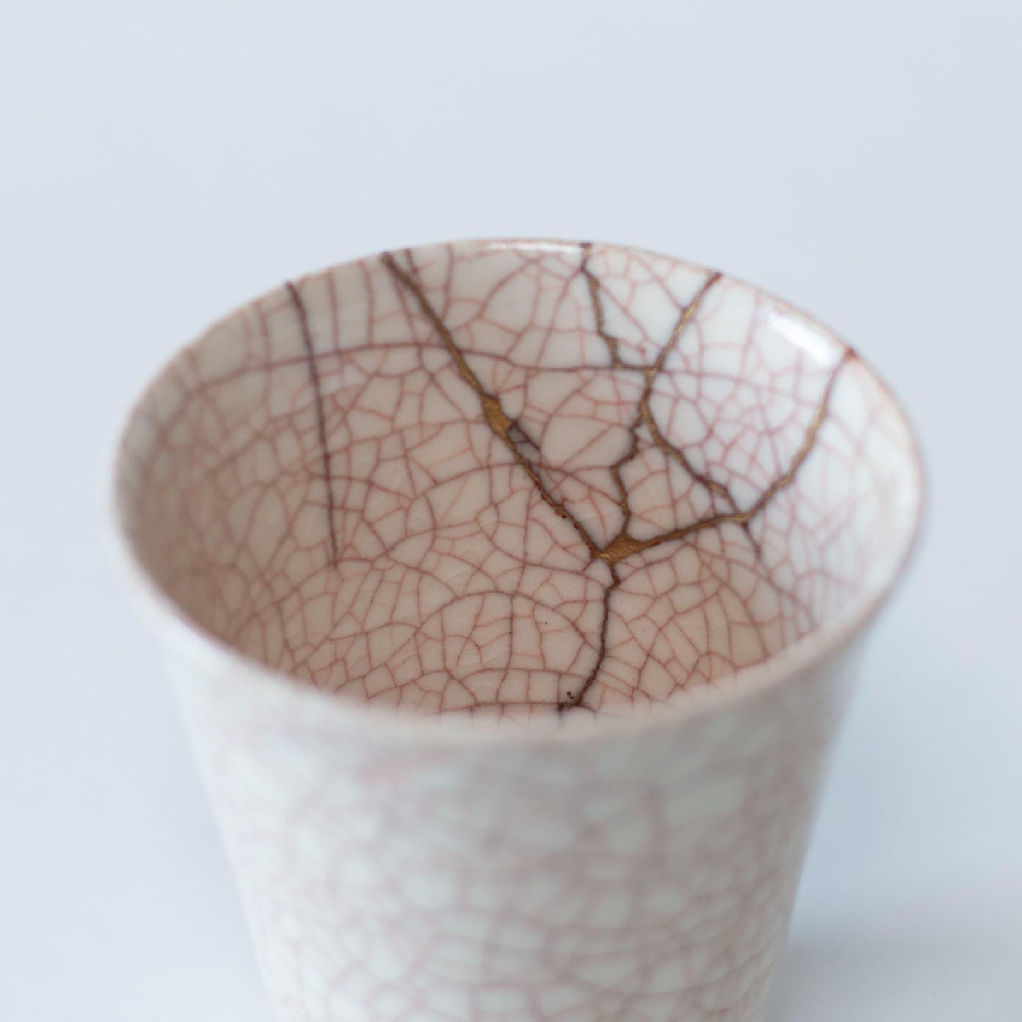 A close-up of the kintsugi repair on the interior of a white ceramic cup, showcasing the beauty of imperfection.