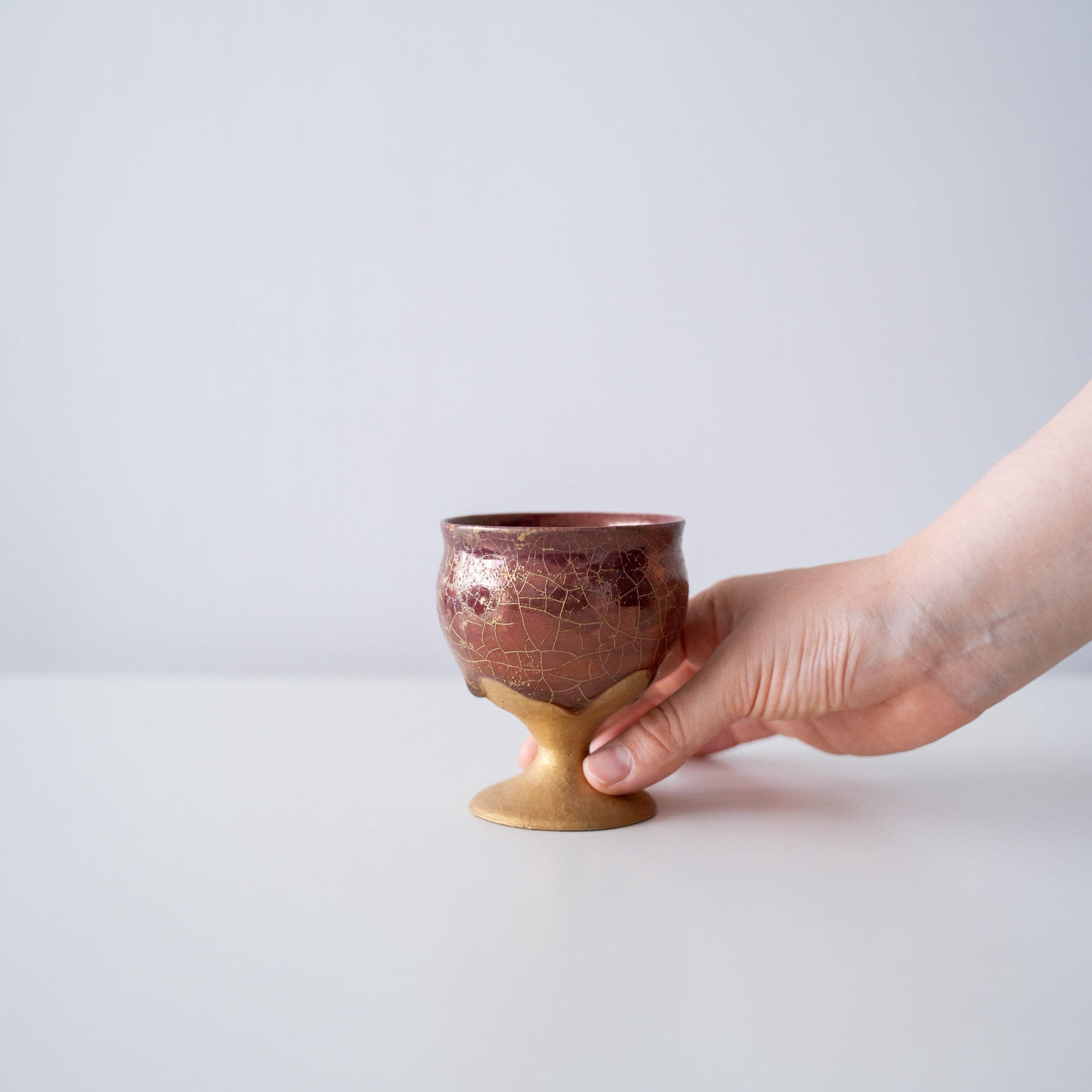 Hand holding Kintsugi Goblet "Gold Clay Crackle", showing its size and how it fits in the hand