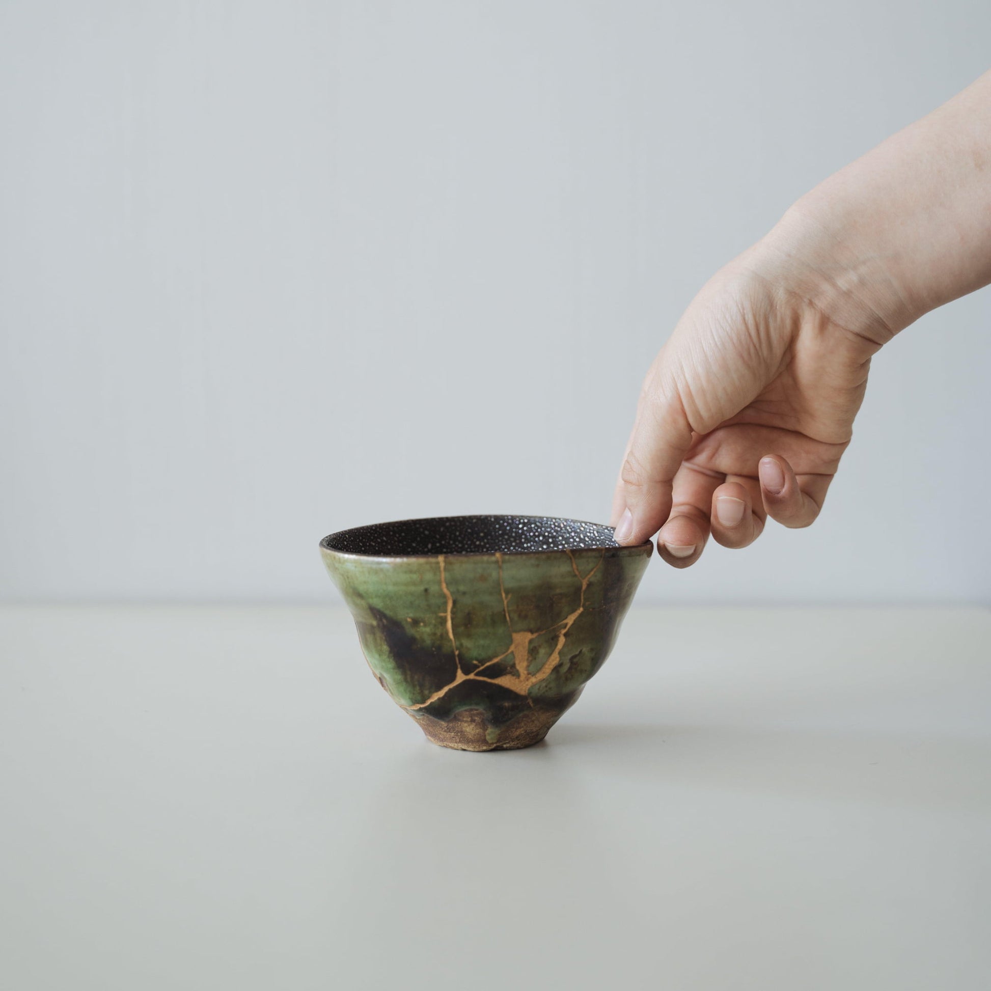 Hand holding Kintsugi Tea Bowl "Starry Sky and Valley", showing its size and how it fits in the hand