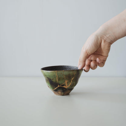 Hand holding Kintsugi Tea Bowl "Starry Sky and Valley", showing its size and how it fits in the hand