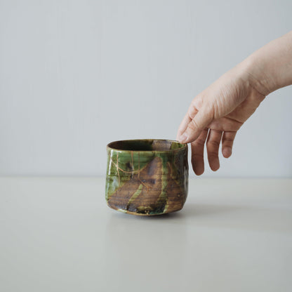 Hand holding Kintsugi Tea Bowl "Valley Oribe", showing its size and how it fits in the hand