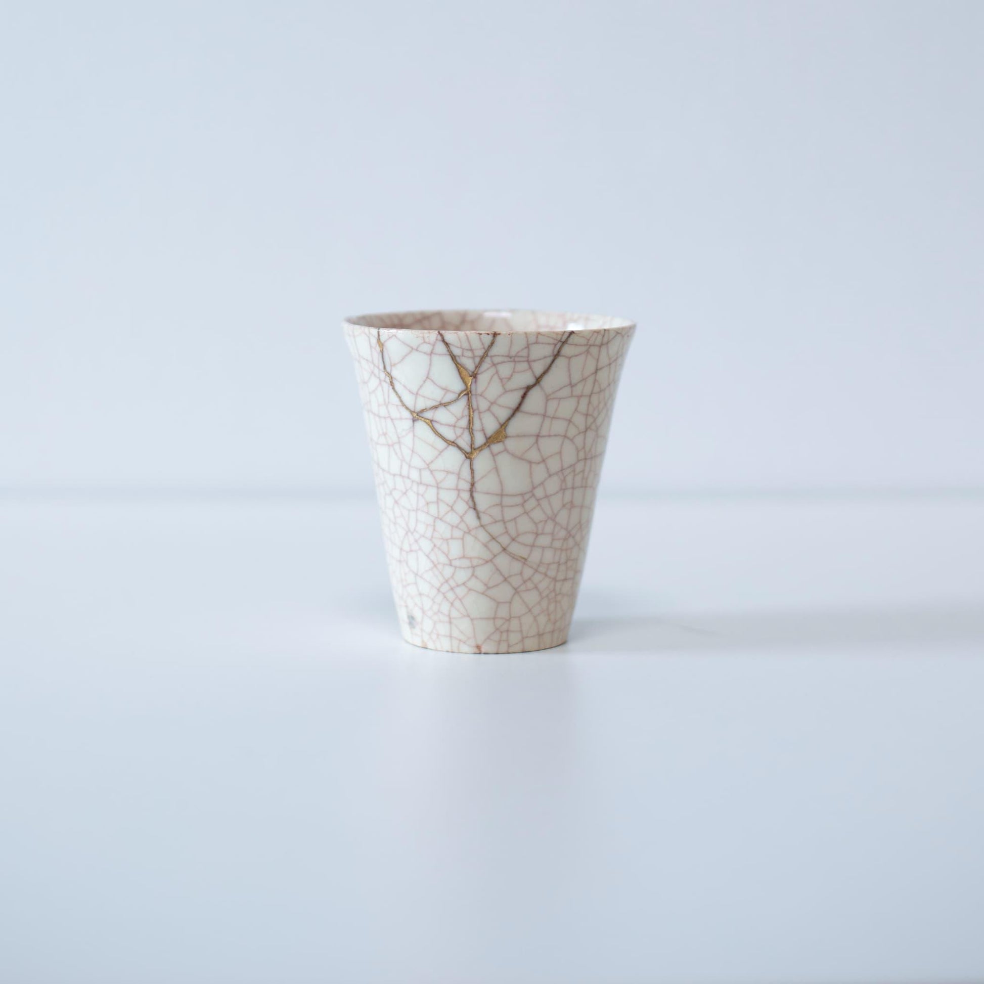 Kintsugi repaired white cup and paulownia wood box gift set, symbolizing the Japanese aesthetic of finding beauty in imperfection.