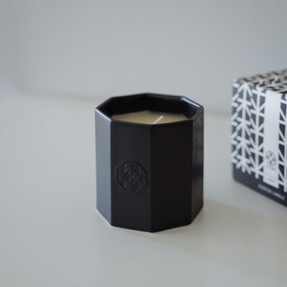 A lit black scented candle made of Arita ware, offering a relaxing wooden fragrance.