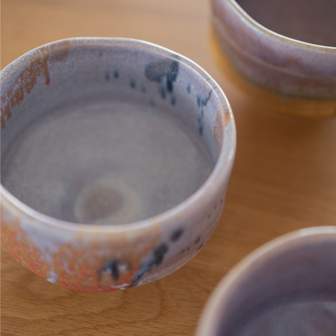 Detailed view of the Navy & Red Splash Japanese matcha chawan bowl, showcasing the unique navy and red glaze droplets applied over the rare Kinyo glaze base by Shinzan Kiln artisans.