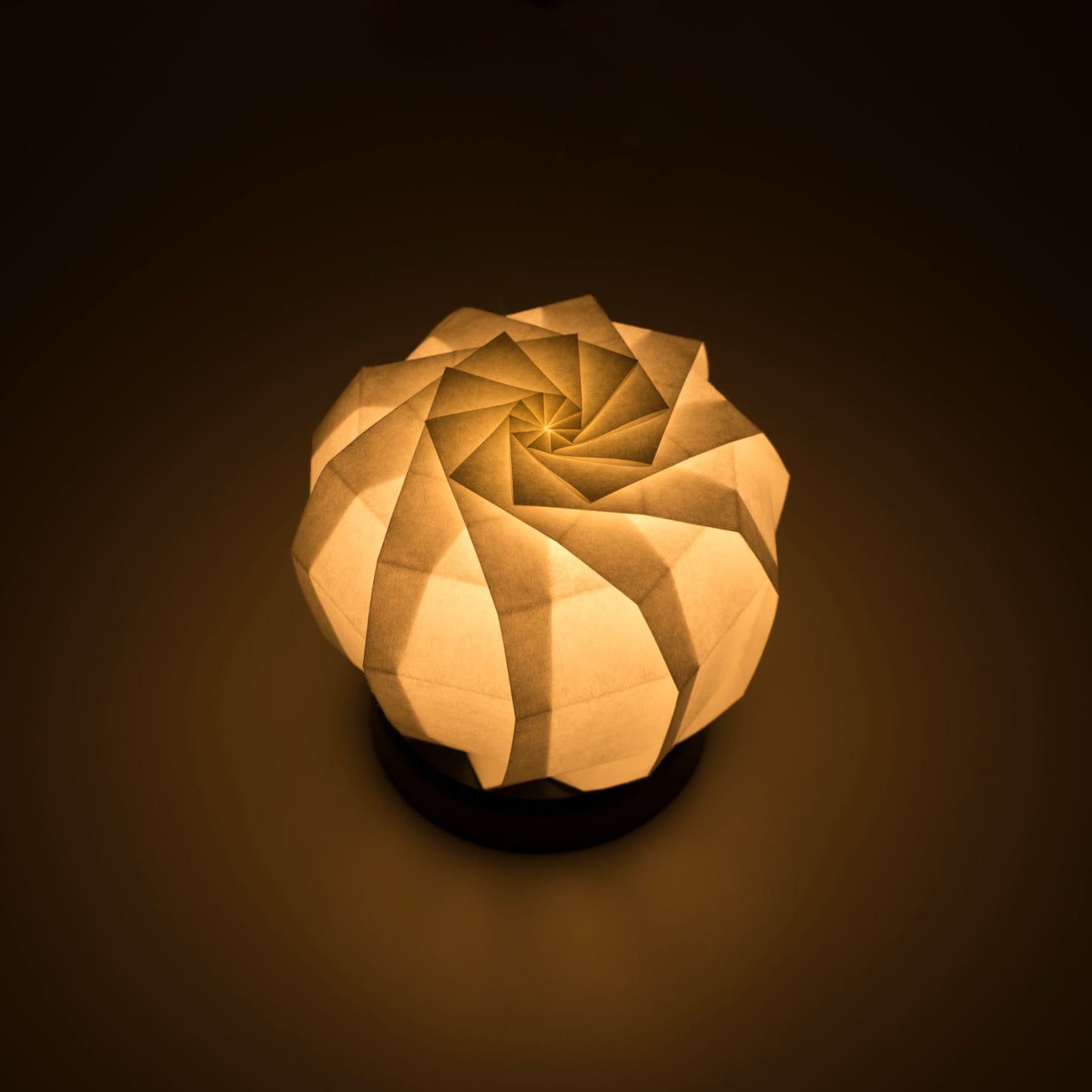Origami Table lamp with a black base and a spherical white lampshade crafted from intricately folded washi paper,  emiting Soft and Warm Light